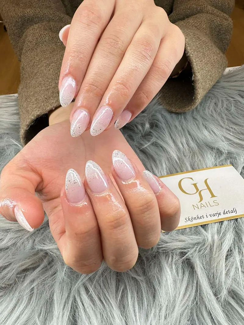 Mandelformade naglar med ljusrosa bas och silvrig glitter-ombré skapade på GH Nails i Örebro.